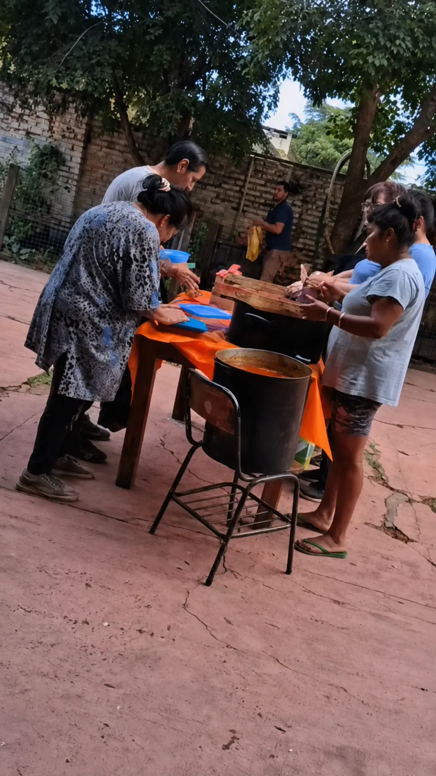 Vecinas y vecinos alrededor de la mesa repartiendo la comida recién hecha.