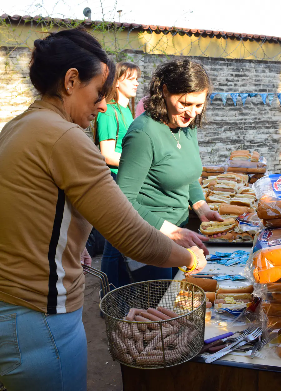 Dos mujeres preparan sándwiches y arman las porciones en la mesa del comedor.