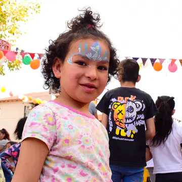 Nena con el pelo recogido y una corona pintada en la cara.
