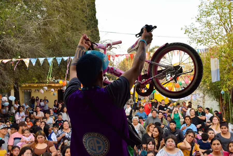 Un voluntario levanta una bicicleta para sortearla frente a una multitud de chicos.
